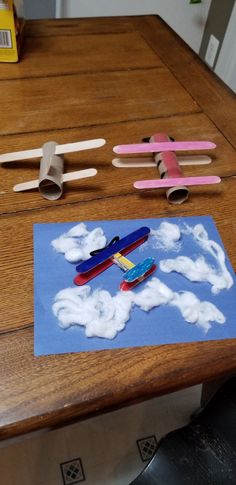 paper airplanes and clouds on a table with crayon sticks sticking out of them