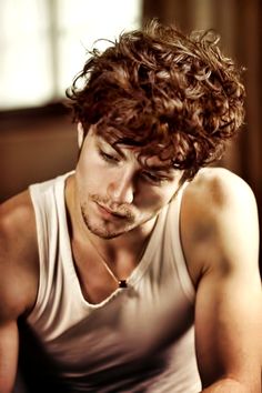 a young man with curly hair sitting down