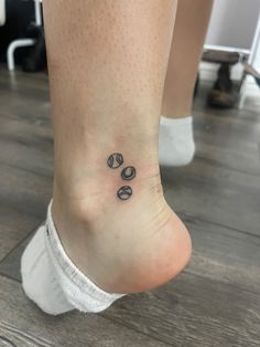 a woman's foot with a small tattoo on her left ankle, and three circles in the middle