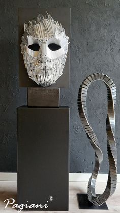 two sculptures made out of metal are sitting on the floor next to each other in front of a black wall