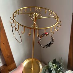 a gold jewelry stand with two rings on it and a vase in the corner next to it