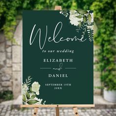 an easel with a sign that says welcome to our wedding and flowers on it