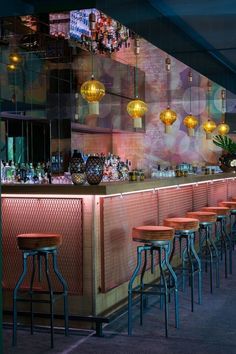 a bar with several stools in front of it and lights hanging from the ceiling