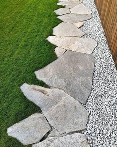 a stone path in the grass between two wooden fences