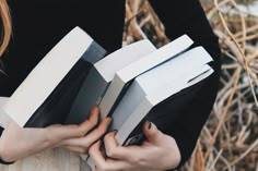 a woman holding several books in her hands