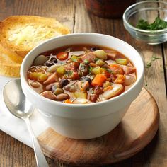 a white bowl filled with soup next to a piece of bread on top of a cutting board