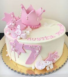 a birthday cake decorated with pink and white frosting, stars and crowns on top