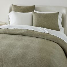 an unmade bed with white pillows and linens in a neutral color scheme,