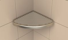 the corner of a shower stall with a metal grate on it's side