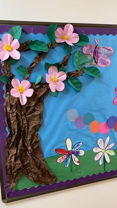 a bulletin board with paper flowers and butterflies on the bottom, in front of a blue background