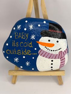 a painted rock with a snowman on it and the words baby its cold outside