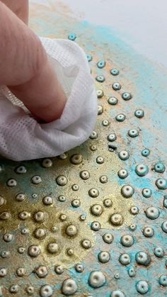 a person wiping down something on top of a blue and gold plate with water droplets