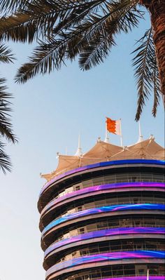 an orange and white flag is on top of a building with palm trees in the foreground