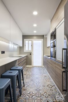 a kitchen with white cabinets and blue stools in front of the counter top area