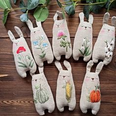 several small stuffed animals sitting next to each other on a wooden surface with leaves and flowers