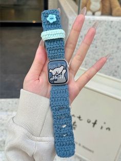 a person holding up a crocheted wristband with an applique on it