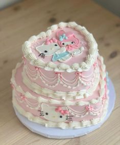 a three tiered cake with hello kitty decorations on the top and bottom, sitting on a wooden table