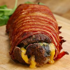 a bacon cheeseburger is cut in half on a cutting board