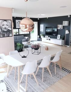 a dining room table with white chairs and pictures on the wall in front of it