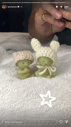 two small figurines sitting on top of a white blanket next to each other