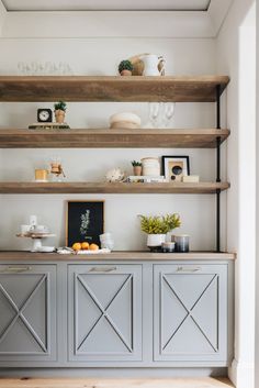 the shelves in this kitchen are made out of wood and have glassware on them