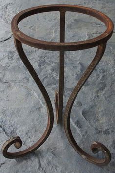 an old iron table with curved legs and a glass top sitting on a stone surface