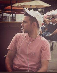 a man with headphones on sitting in front of an outdoor bar while people sit at tables