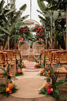 an outdoor ceremony set up with wicker chairs and tropical flowers on the aisle, surrounded by palm trees