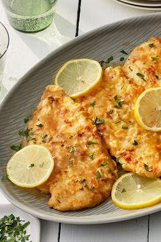 two pieces of fish with lemons and parsley on the side