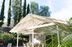 an outdoor covered patio with lounge chairs and trees in the backgroung area