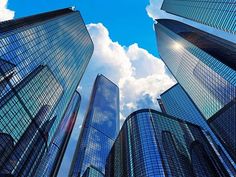 looking up at tall buildings with blue sky and clouds in the backgrounnd