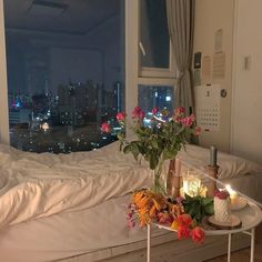 a table with flowers and candles on it in front of a window overlooking the city