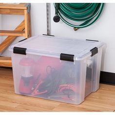 a plastic storage box filled with lots of different types of cords and other things on the floor