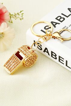 a gold keychain with a red and white diamond on it sitting next to a book