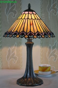 a table lamp sitting on top of a table next to a cup and saucer