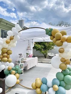 an arch made out of balloons and streamers in the middle of a patio area