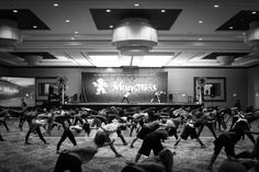 a large group of people are doing yoga in a room with lights on the ceiling