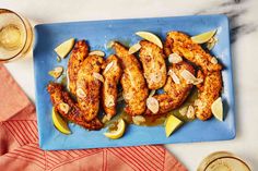 grilled chicken with lemons and almonds on a blue platter next to two glasses of beer