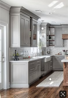 a large kitchen with wooden floors and gray cabinets