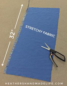 a pair of scissors sitting on top of a piece of blue fabric with the words stretchy fabric next to it