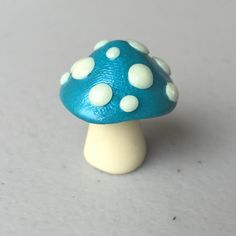 a small blue mushroom with white dots on it's top sitting on a table