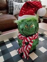 a green stuffed animal sitting on top of a checkered table next to a christmas hat