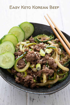 a bowl filled with beef and cucumbers next to chopsticks