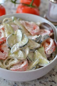 a white bowl filled with pasta and veggies on top of a marble counter