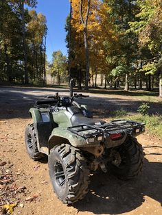 an atv is parked in the dirt near some trees