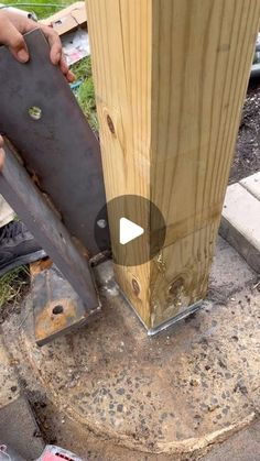 a person is holding a piece of wood near a pole and some other items on the ground