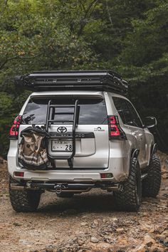 the back end of a silver toyota 4x4 parked on a rocky trail with trees in the background