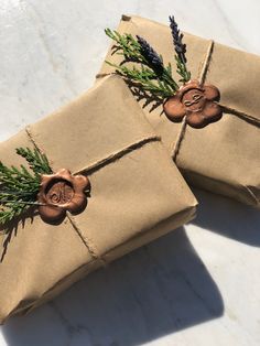 two wrapped presents tied with twine and decorated with lavenders, rosemary and wax