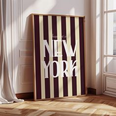 there is a new york poster on the floor in front of a window with curtains