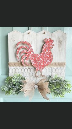 a red rooster sitting on top of a wooden sign